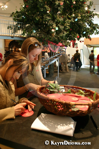 Two women write wishes on pomegranate shaped paper to tie onto the pomegranate tree at the Jewish Museum Berlin, Germany.