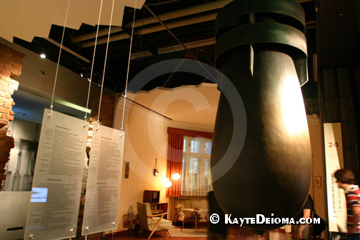 A bomb suspended from the ceiling divides model living rooms from the east and west at the Story of Berlin.