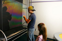 Becca watches as Derick creates a wall of soap bubble at the Great Lakes Science Center.