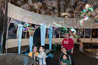A boy turns a wheel that creates a giant bubble that spreads around the room in the Burbujas section of Trompo Magico.