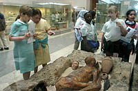 Children gather around a Predynastic Egyptian Man known as Ginger, whose skin and flesh were preserved by burial in the dry sand of the desert. British Museum, London.