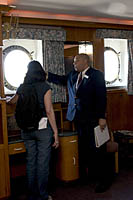 Tour guide Joe Goff explains to a visitor how windows rolled down to cover the portholes aboard the RMS Queen Mary if the water was high to avoid frightening passengers.