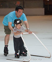 A father teaches his son to skate using the Easy Skater at Atrium Le 1000 in Montreal. Š Kayte Deioma
