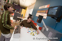 A teenage boy operates the camera as his dad moves plastic pieces on a white table to create an animation at the Zeum in San Francisco.