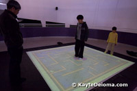 A boy uses his weight to move a virtual marble around the MetaField Maze at the Zeum in San Francisco.